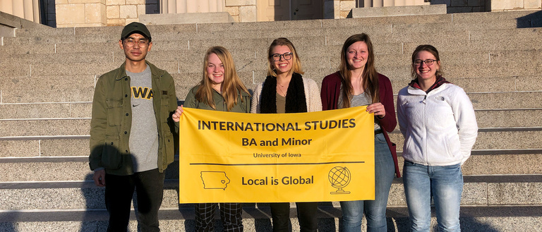 Group of international studies majors holding a flag