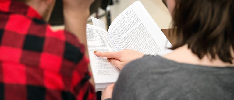 Two people look at a translated book