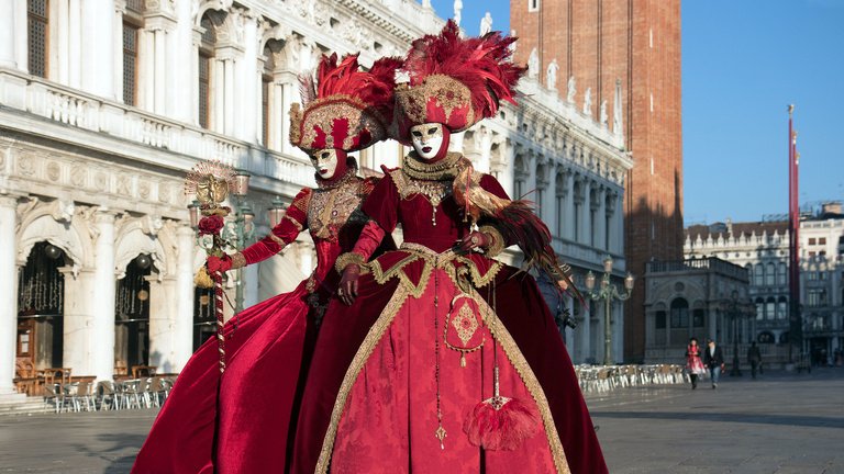 Two people pose in masks during Carneval in Venice