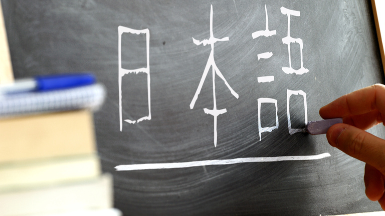 Japanese characters being written on a chalkboard