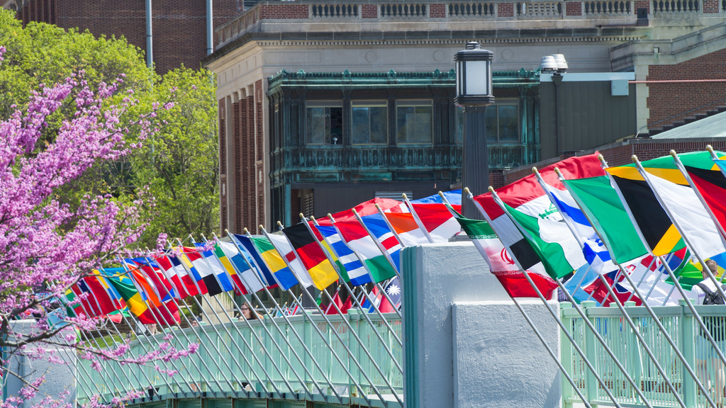 International flags flapping in the wind over a footbridge on the University of Iowa campus